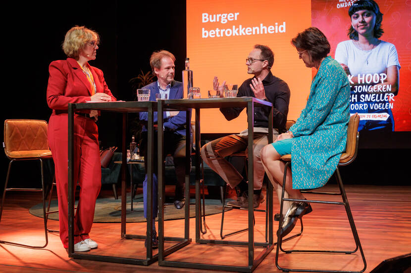 2 vrouwen en 2 mannen in gesprek aan een tafel op een podium